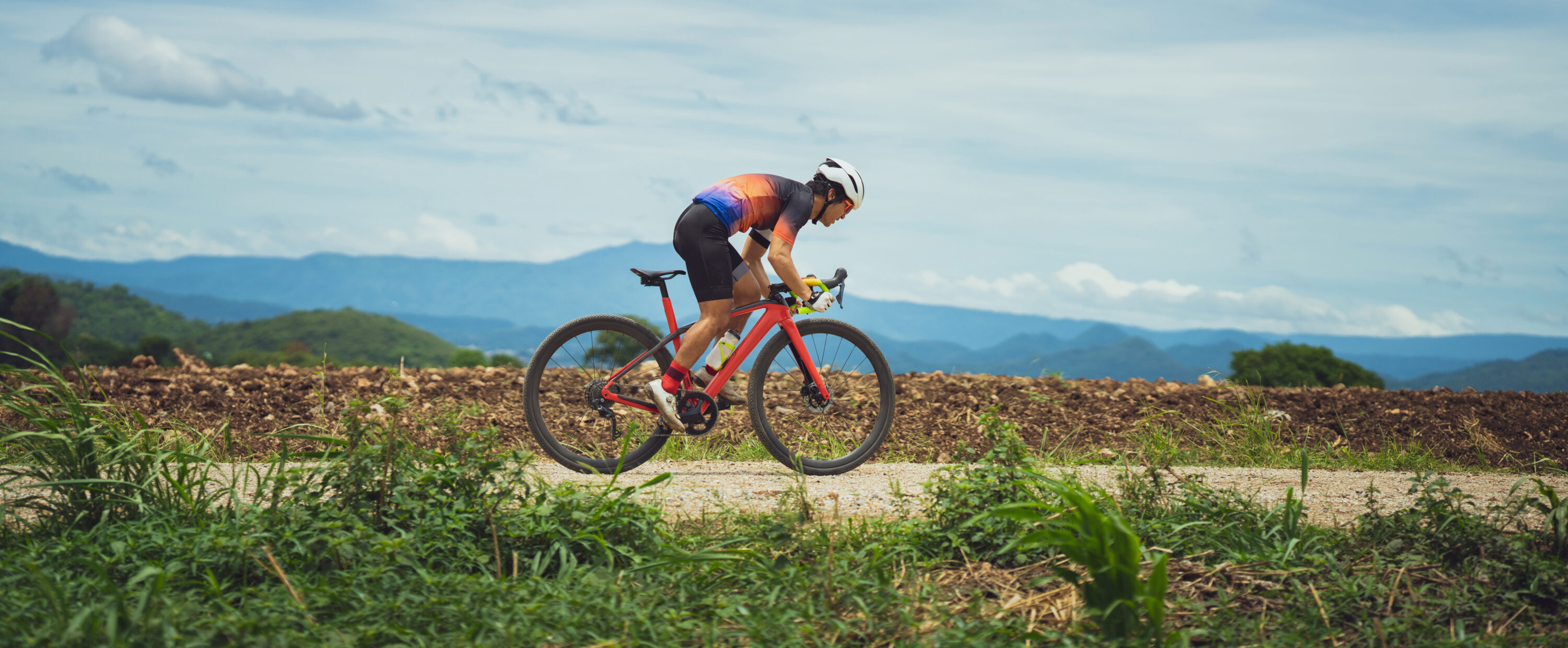 Asian man cycling on gravel road.